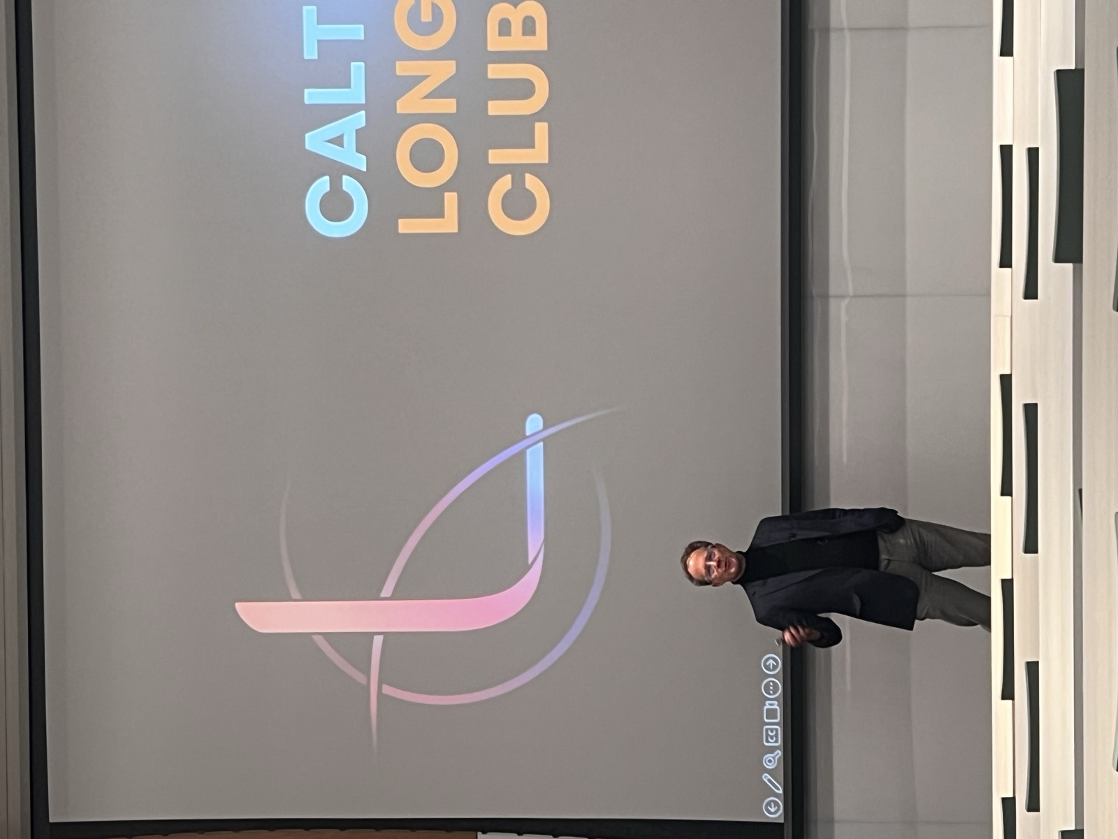 Speaker in front of the Caltech Longevity Club logo
